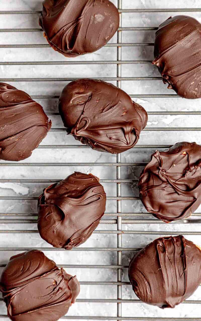 Peanut butter eggs freshly dipped in chocolate on a wire rack.