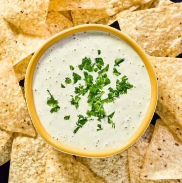 Copycat Chuy's creamy jalapeno dip and tortilla chips on a round platter.