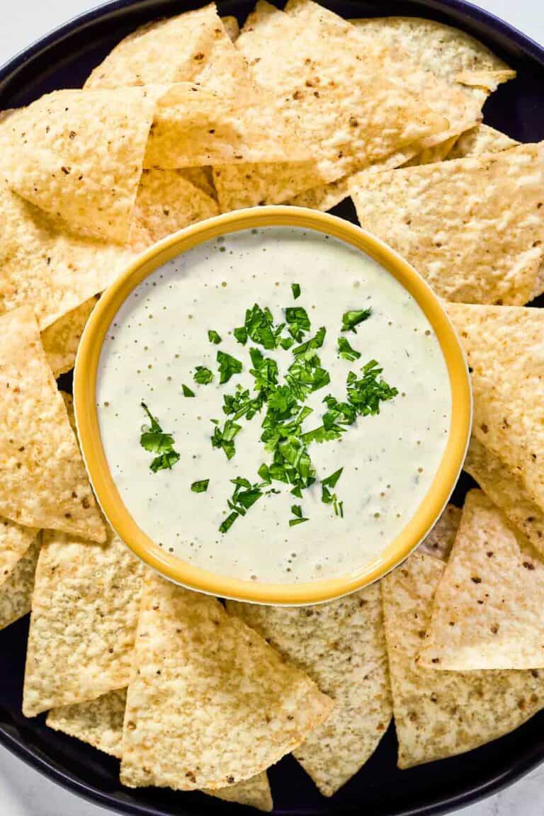 Copycat Chuy's creamy jalapeno dip and tortilla chips on a round platter.