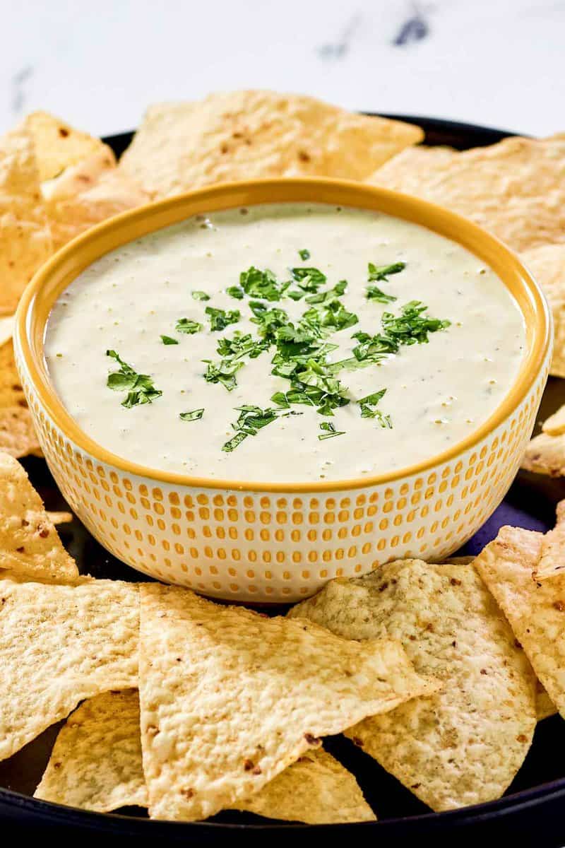 Copycat Chuy's creamy jalapeno dip in a bowl and tortilla chips around it.