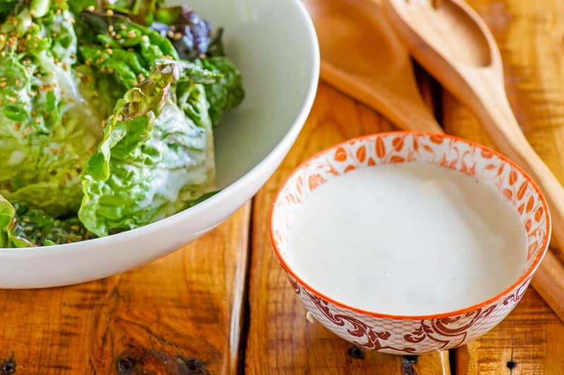Homemade Japanese salad dressing in a small bowl and a salad next to it.