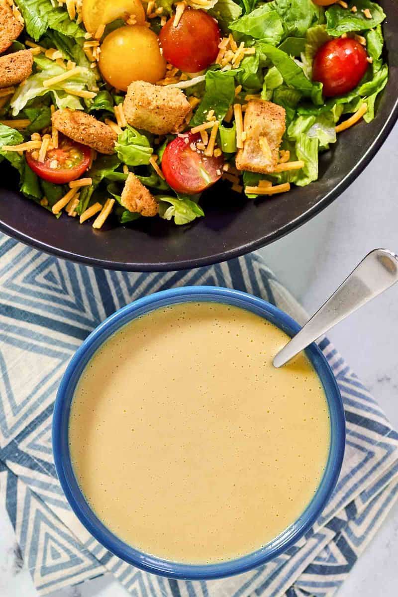 A salad and a bowl of copycat Outback honey mustard dressing.
