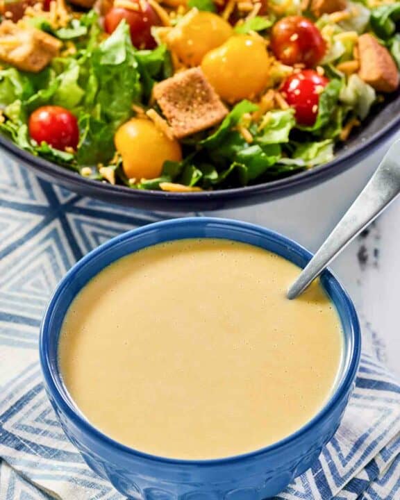 Copycat Outback honey mustard dressing in a bowl and a salad.