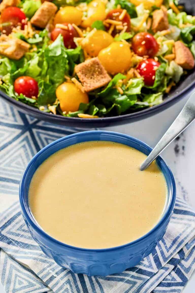 Copycat Outback honey mustard dressing in a bowl and a salad.