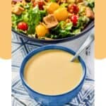 Homemade Outback honey mustard dressing in a bowl and a salad behind it.