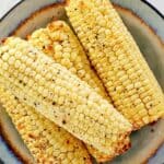 Four ears of air fried corn on the cob on a plate.