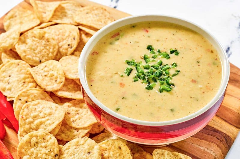 Copycat Chipotle queso blanco in a bowl and tortilla chips beside it.