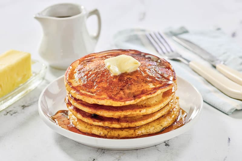 A stack of copycat IHOP protein pancakes with butter and syrup on a plate.