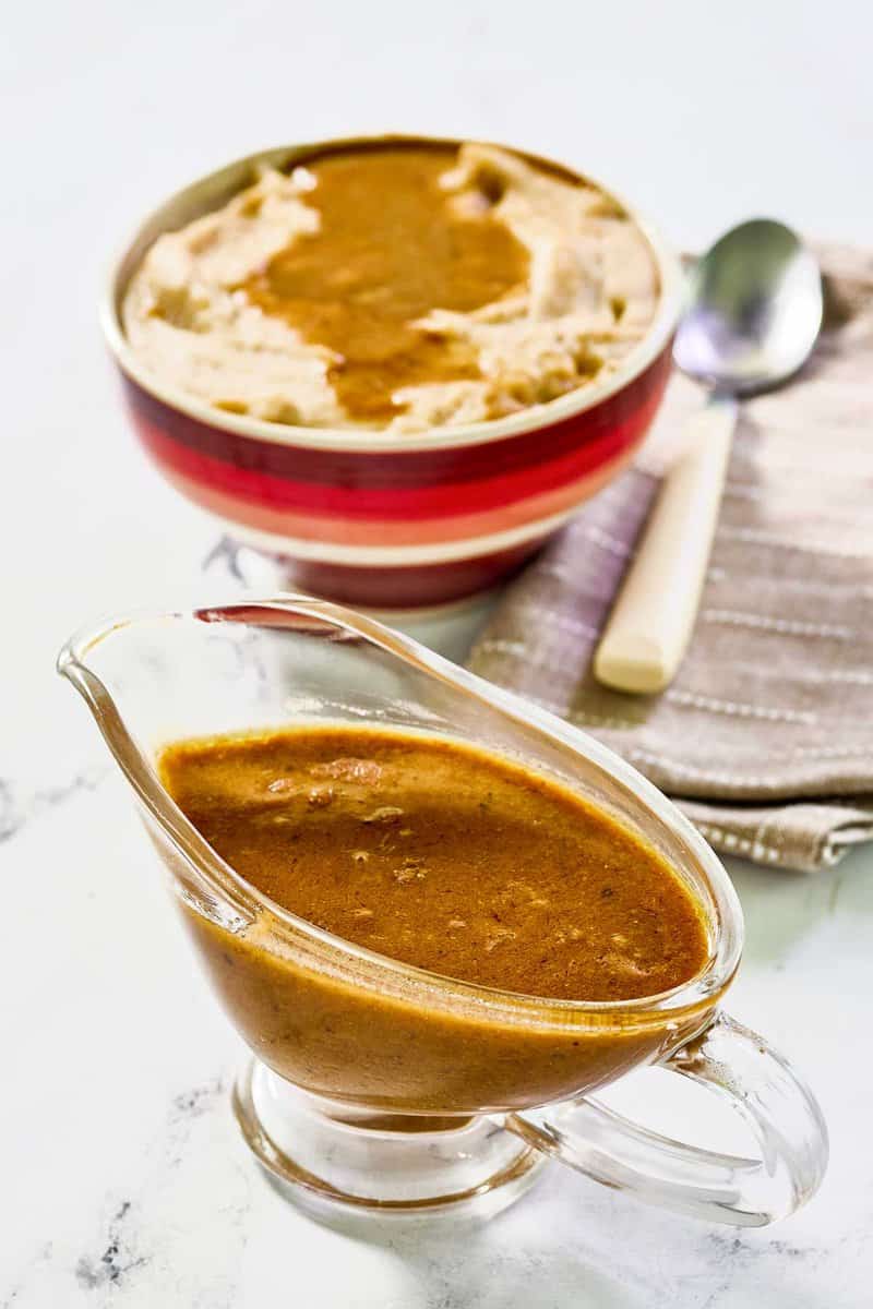 Copycat KFC gravy in a gravy boat and on top of mashed potatoes.