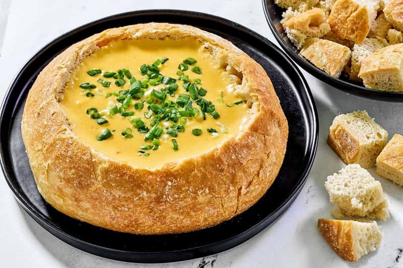 Copycat Red Lobster ultimate fondue in a bread bowl and some bread cubes by it.
