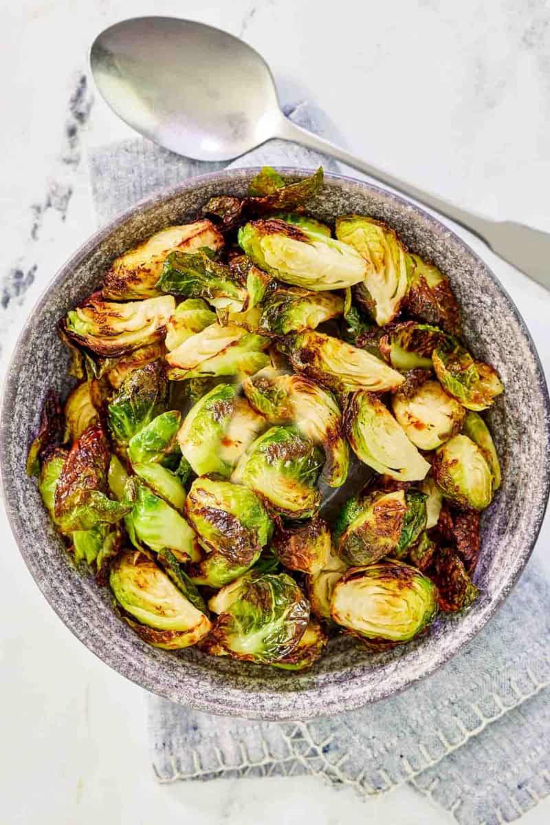 Air fryer Brussels sprouts in a bowl and a spoon next to it.