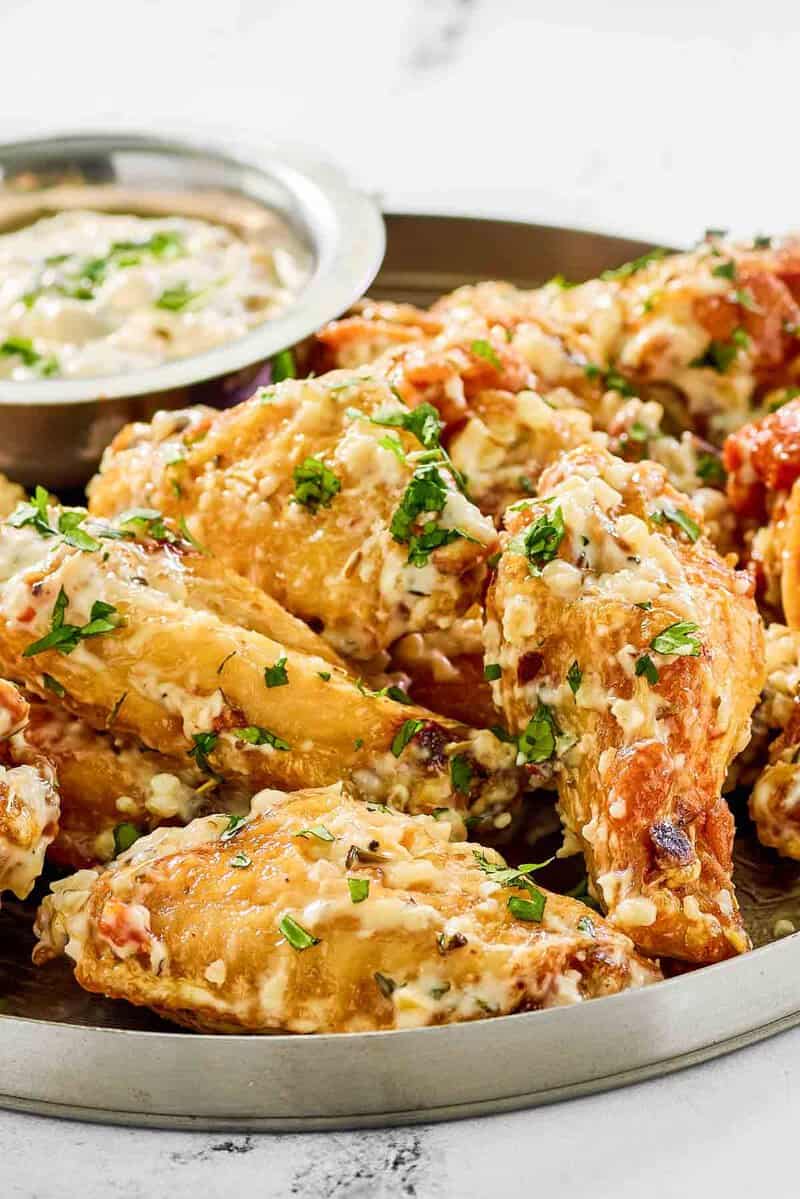 Copycat Buffalo Wild Wings garlic parmesan wings and sauce on a plate.