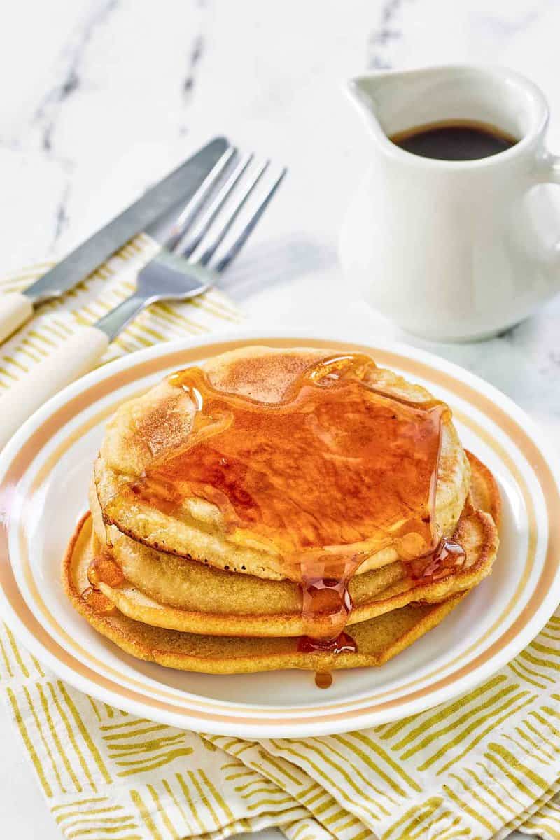 A stack of copycat McDonald's pancakes with buttery maple syrup on a plate.