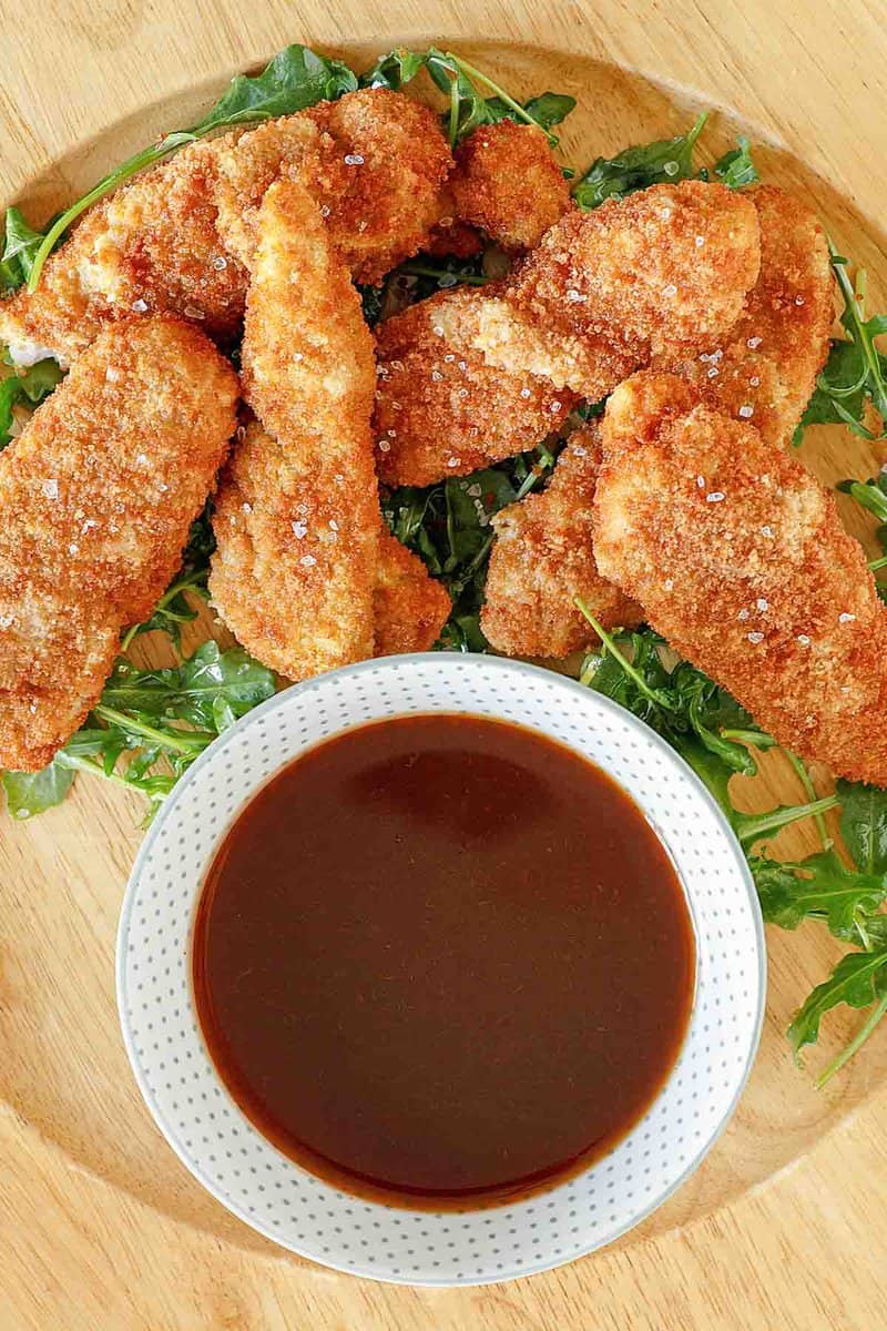 A bowl of copycat TGI Friday's jack daniels dipping sauce and chicken fingers.