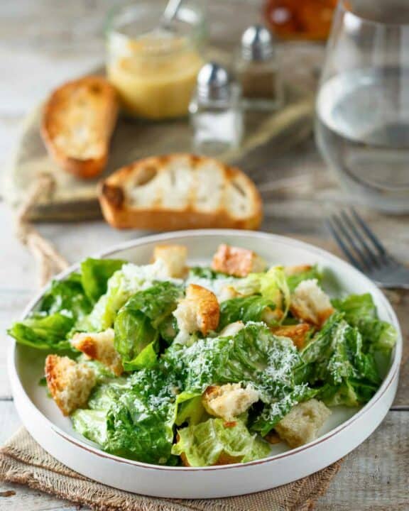 Copycat Anthony's Caesar salad, toasted bread slices, and a jar of dressing.
