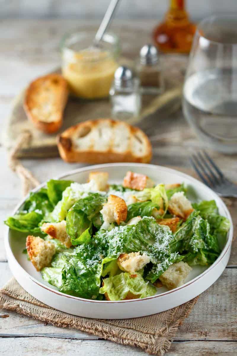 Copycat Anthony's Caesar salad, toasted bread slices, and a jar of dressing.