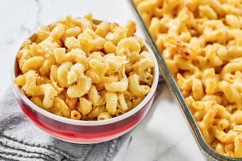 Copycat Costco mac and cheese in a bowl next to it in a baking dish.