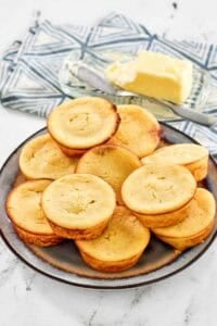 Copycat Cracker Barrel cornbread muffins on a plate and butter behind it.