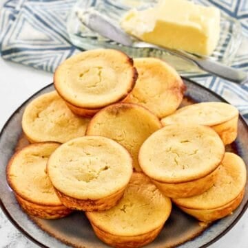 Copycat Cracker Barrel cornbread muffins on a plate and butter behind it.