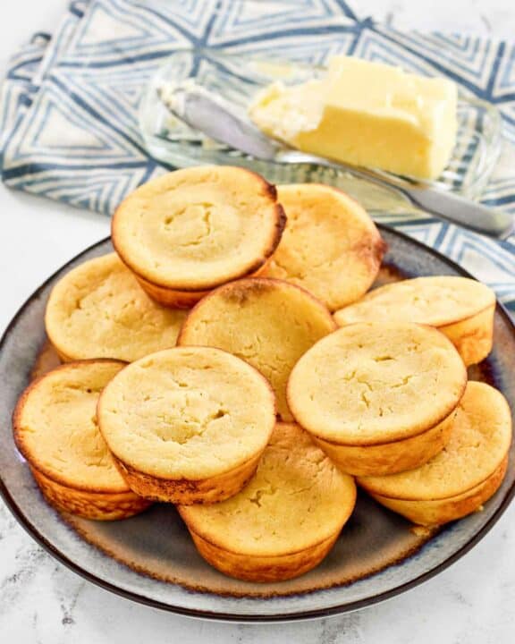 Copycat Cracker Barrel cornbread muffins on a plate and butter behind it.