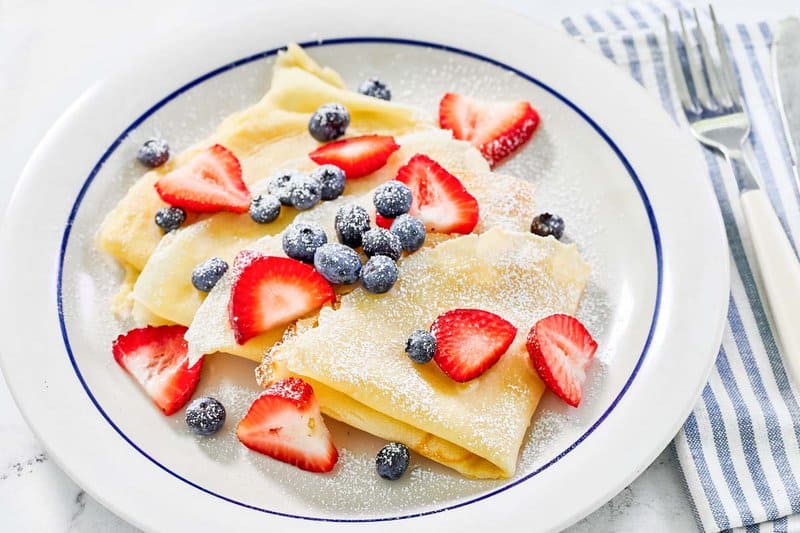 Copycat IHOP crepes with fresh blueberries and strawberries on top.