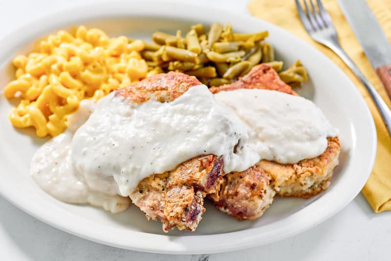 Copycat Cracker Barrel country fried pork chops with gravy, mac and cheese, and green beans.