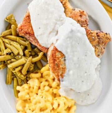 Two copycat Cracker Barrel country fried pork chops with gravy.