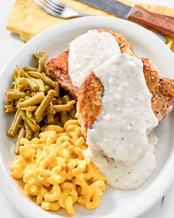 Copycat Cracker Barrel country fried pork chops with gravy, green beans, and mac and cheese.