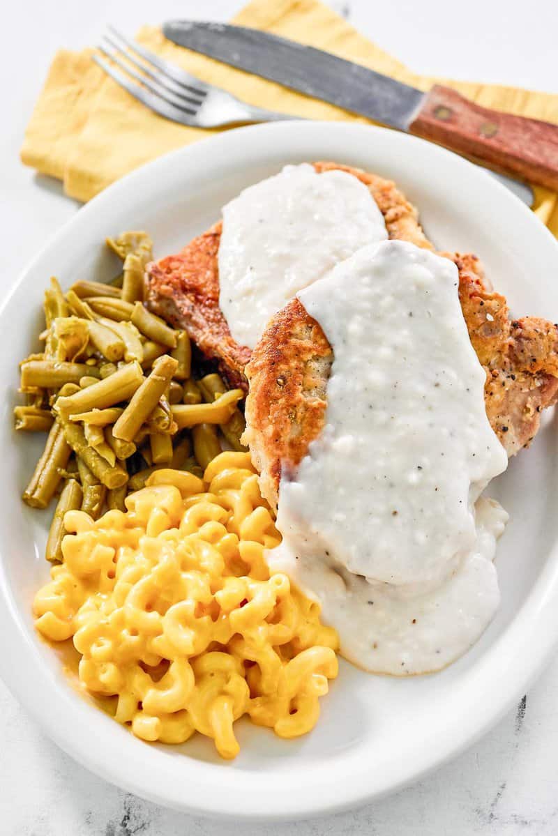 Copycat Cracker Barrel country fried pork chops with gravy, green beans, and mac and cheese.