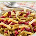 Grandma's 3 bean salad in a serving bowl and a slotted spoon behind it.