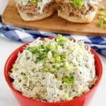 Copycat Houston's coleslaw in a bowl and two pork sliders with it on a wood board.