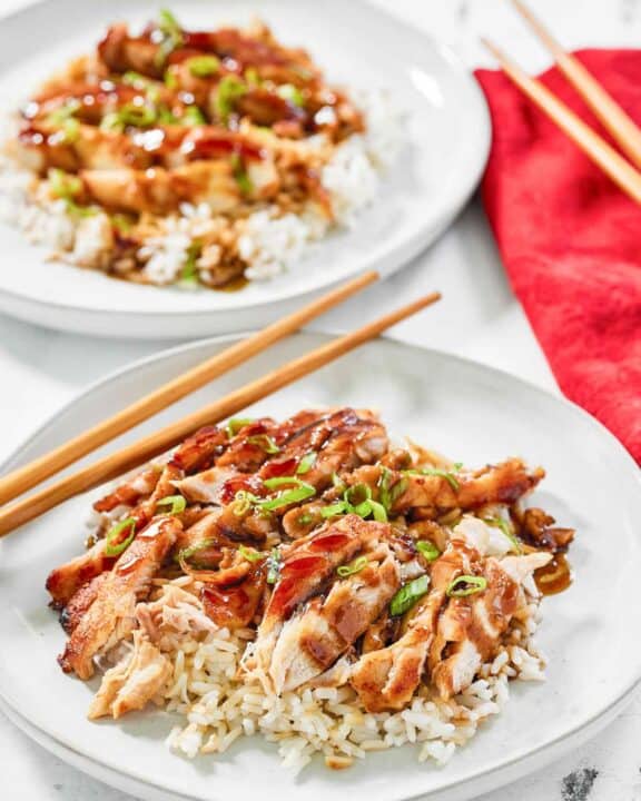 Copycat Panda Express grilled teriyaki chicken over rice on two plates.