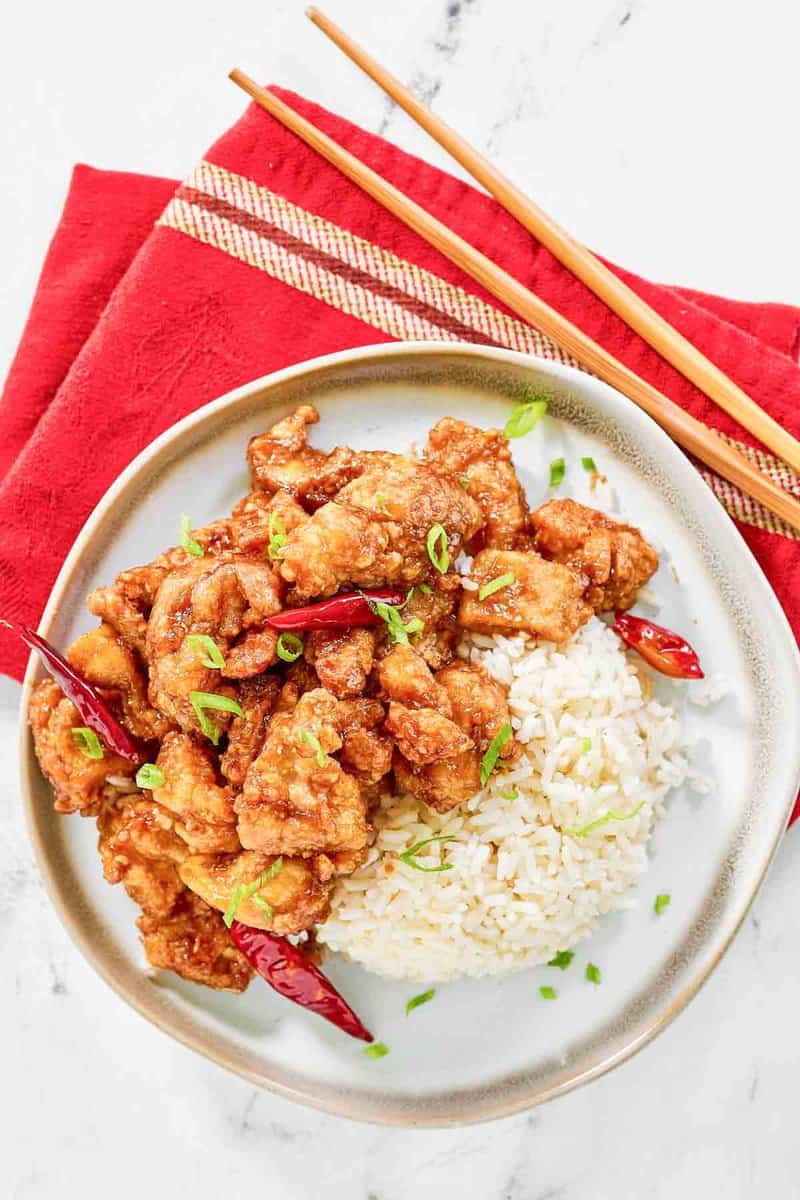 Copycat Panda Express hot orange chicken and steamed white rice on a plate.