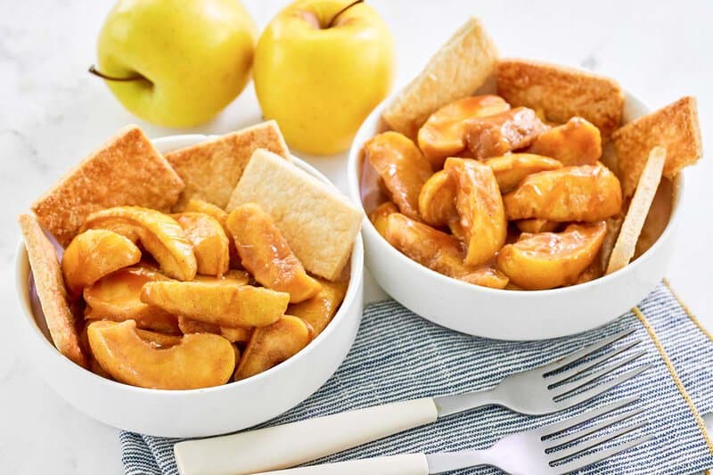 Bowls of copycat cracker barrel southern apple cobbler and two apples.