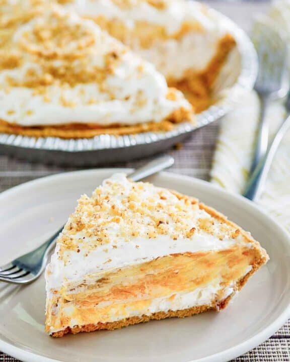 Double layer pumpkin pie and a slice on a plate in front of it.