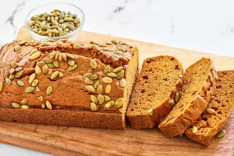 Copycat starbucks pumpkin bread and a small bowl of pumpkin seeds.