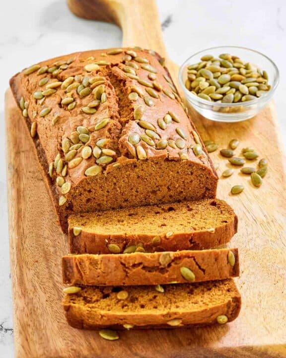 Copycat starbucks pumpkin bread and a small bowl of pumpkin seeds.