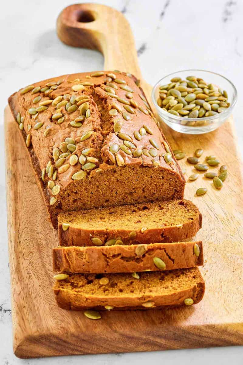 Copycat starbucks pumpkin bread and a small bowl of pumpkin seeds.