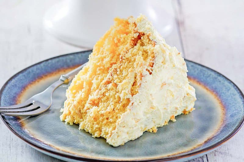 A slice of ambrosia cake and a dessert fork on a plate.