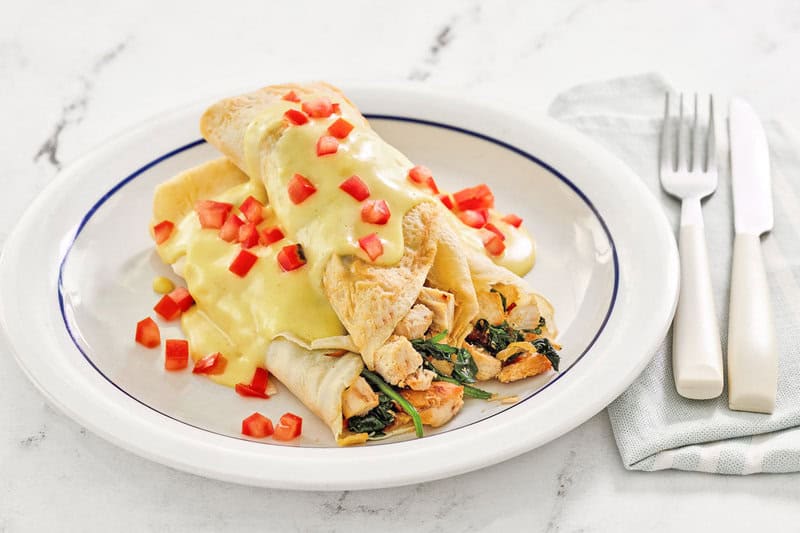 Copycat ihop chicken florentine crepes with hollandaise sauce and tomatoes on top.