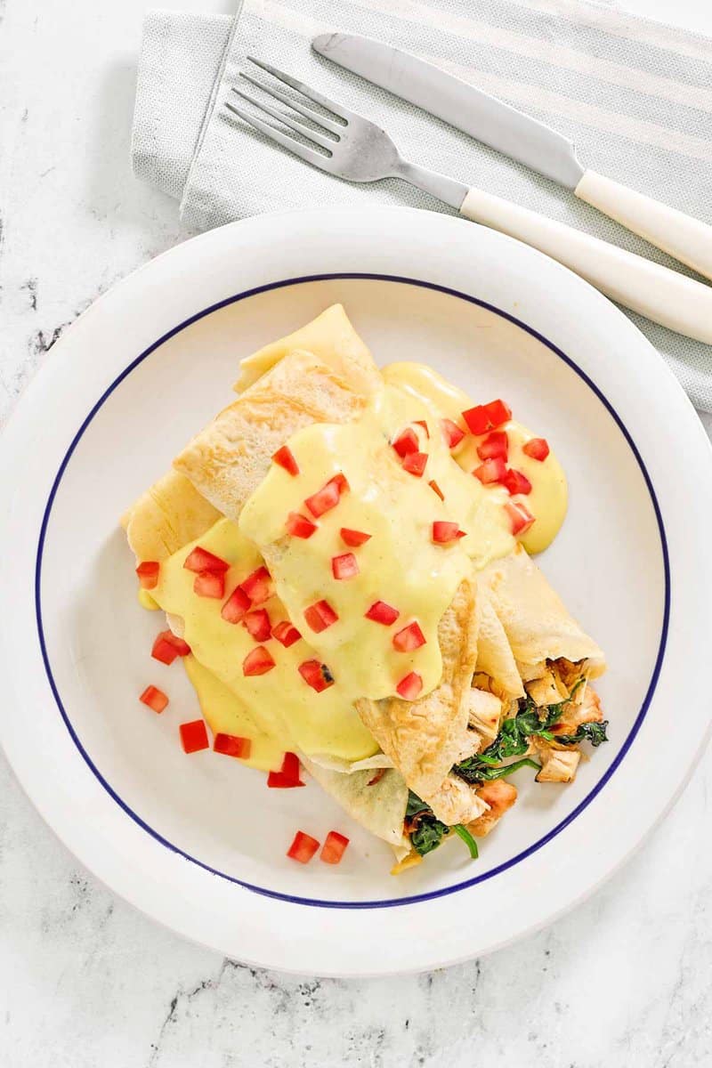 Copycat ihop chicken florentine crepes with hollandaise sauce on a plate.