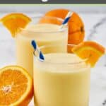 Homemade orange julius in glasses and fresh oranges beside them.