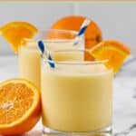 Homemade orange julius in glasses and an orange half.