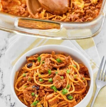 Taco spaghetti casserole in a baking dish and a serving in a bowl.