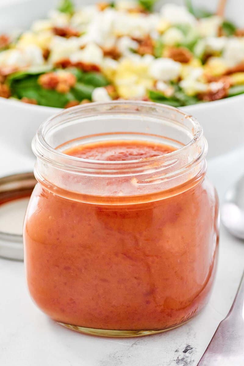 Copycat Bennigan's hot bacon dressing in a mason jar and a salad.