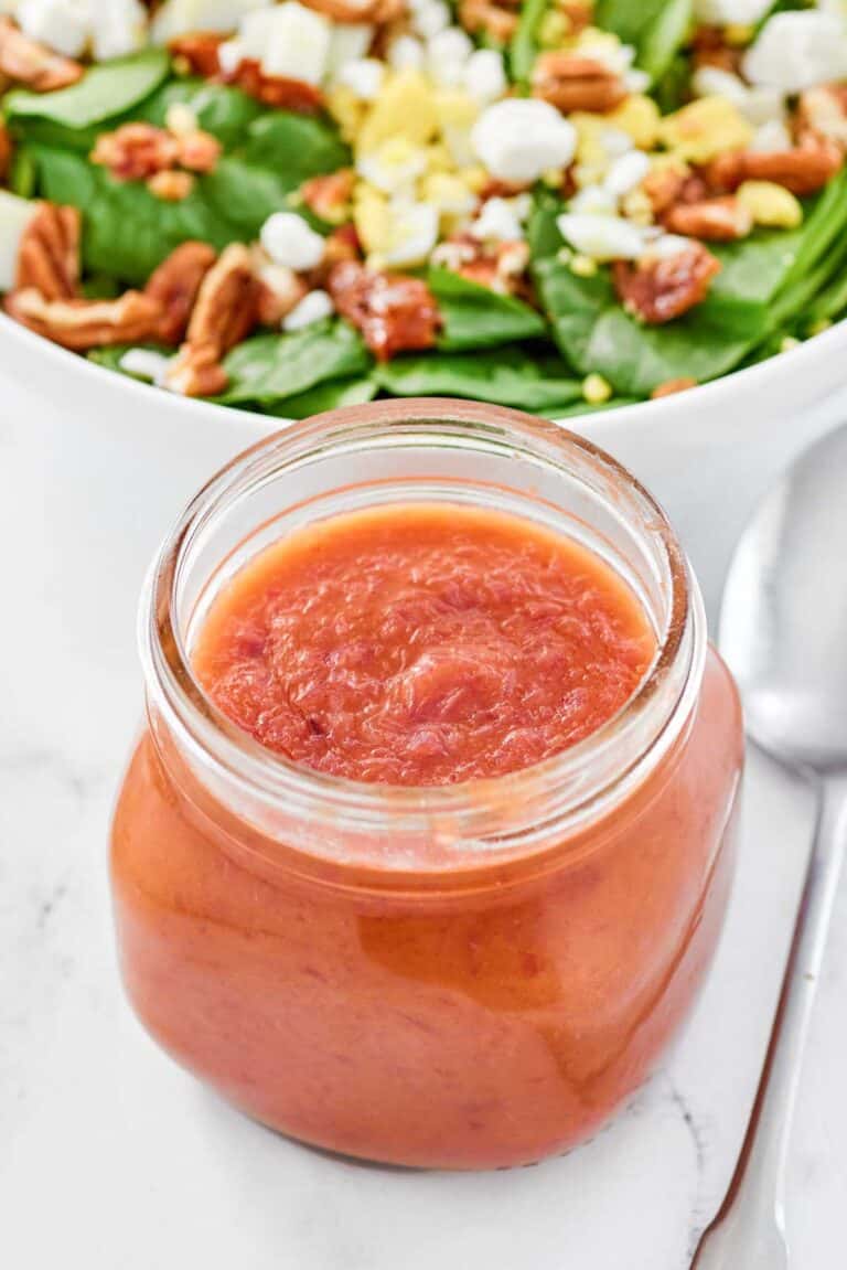Copycat Bennigan's hot bacon dressing in a jar and a salad behind it.