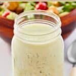 Homemade buttermilk ranch dressing in a mason jar in front of a salad.