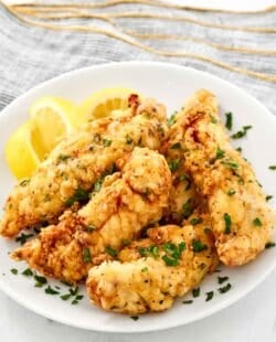 Copycat Piada chicken tenders and lemon wedges on a plate.