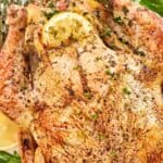 A whole roasted chicken, lemon slices, and herbs.