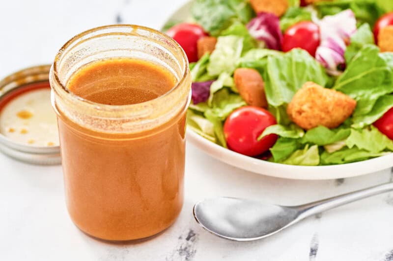 Copycat state fare lemon vinaigrette salad dressing in a jar and a salad next to it.